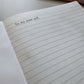 Open notebook with lined pages and text 'To my past self' on a wooden surface.